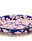 Plato hondo de peltre azul con manchas rosas y borde azul.