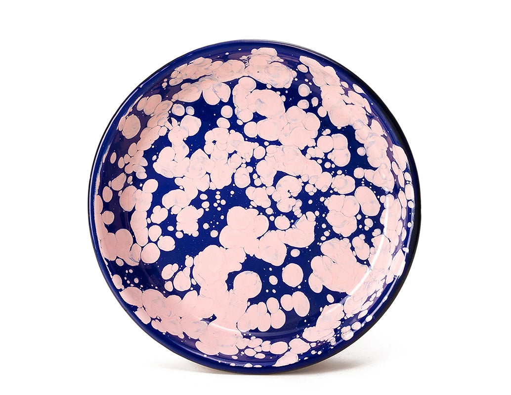 Plato hondo de peltre azul con manchas rosas y borde azul.